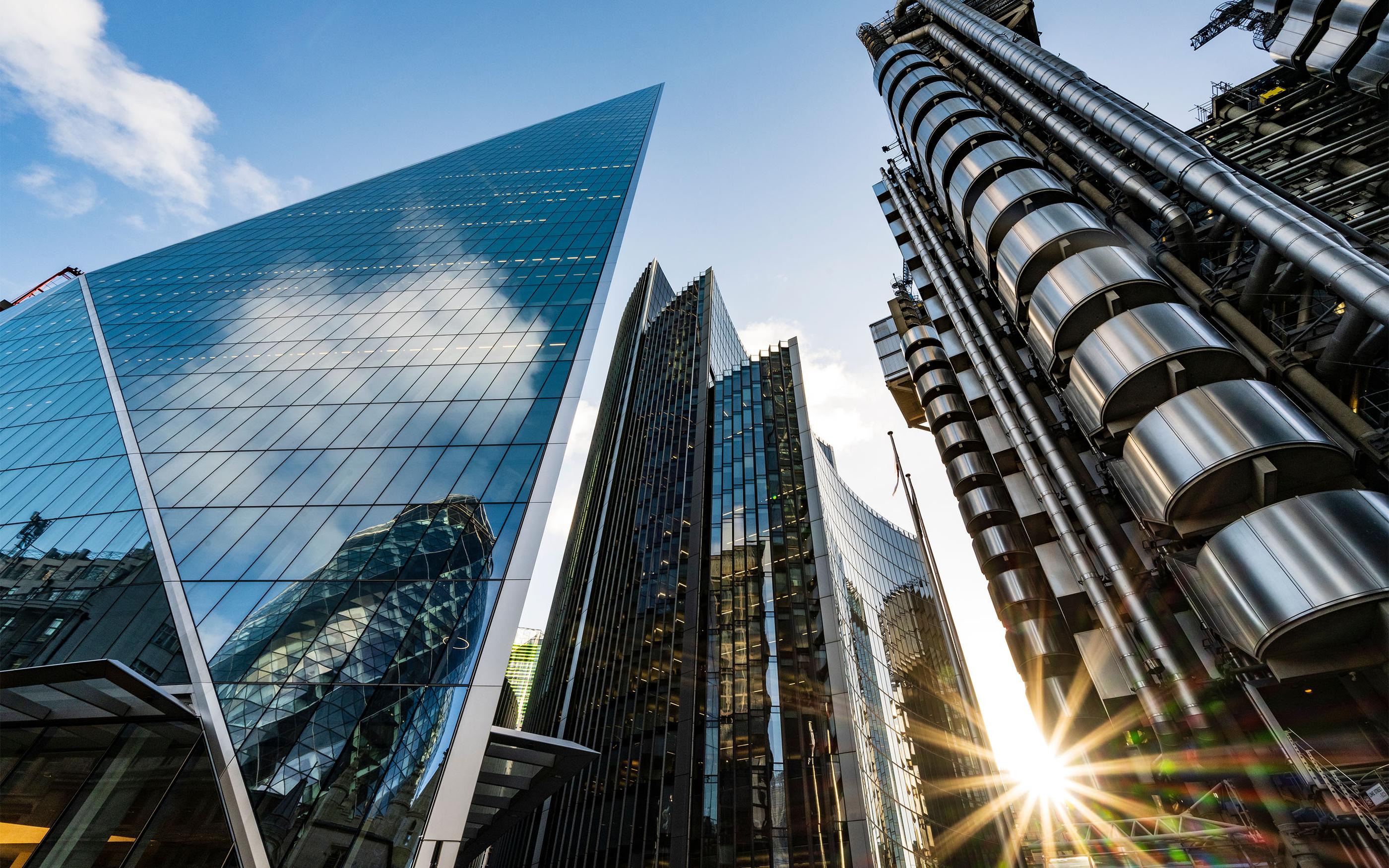Low-angle view of modern glass and steel skyscrapers reflecting the sky in a major financial district.