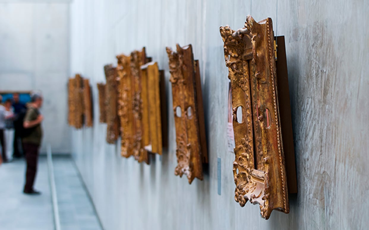 A row of organic, wooden sculptures mounted on a white gallery wall.