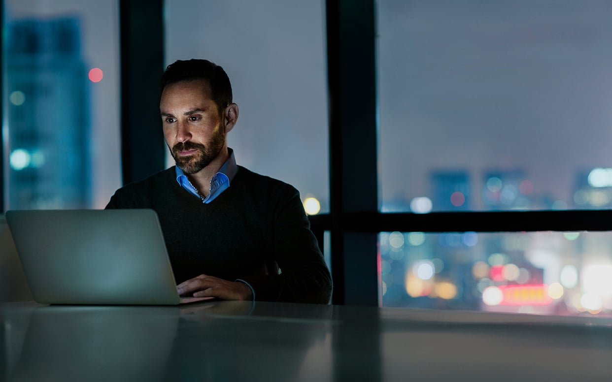 Man viewing laptop computer in office at night