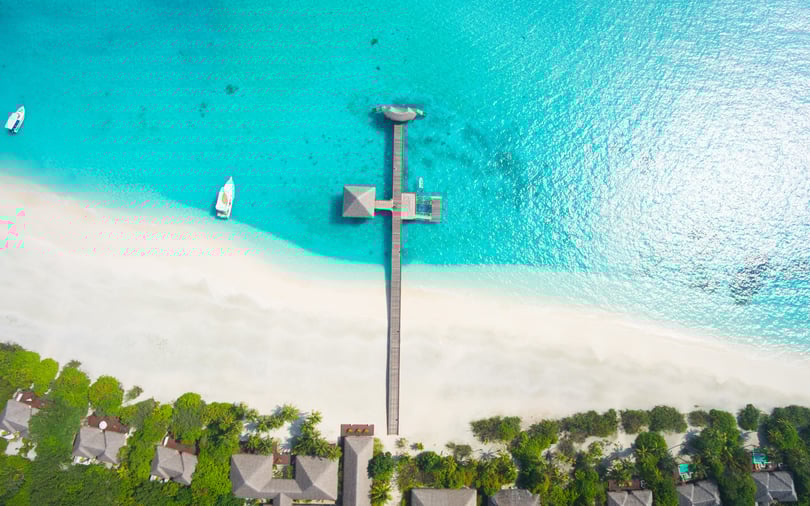 A tall observation or communications tower situated on a tropical coastline with clear blue water.