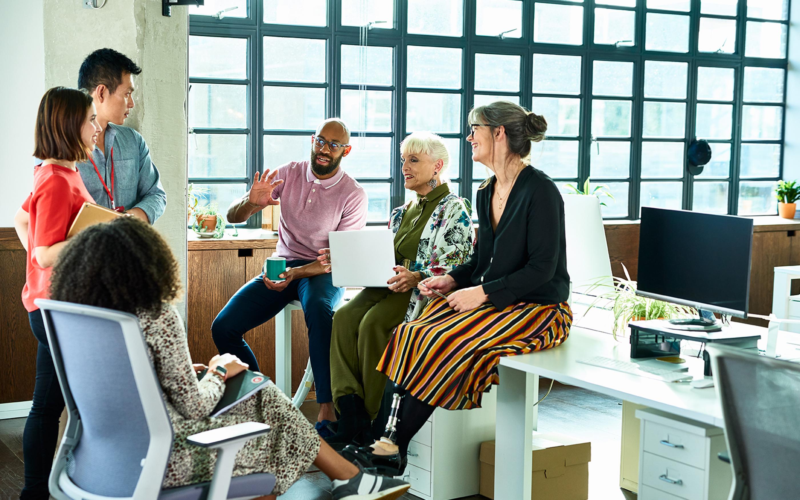 Business colleagues in meeting with disabled female sitting on desk