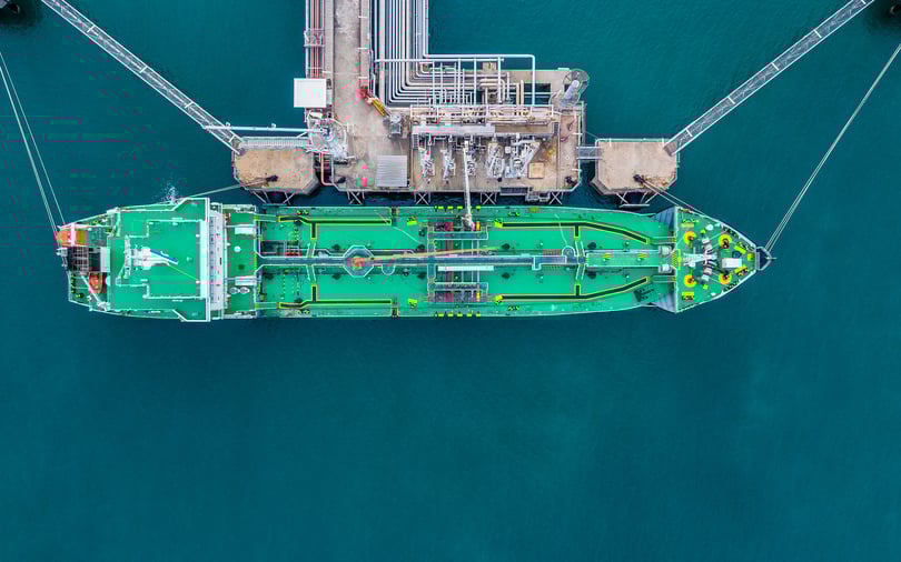 Front-facing view of a massive green and red cargo vessel navigating through deep blue water.