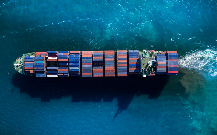 A large blue container ship carrying multi-colored freight across the ocean.