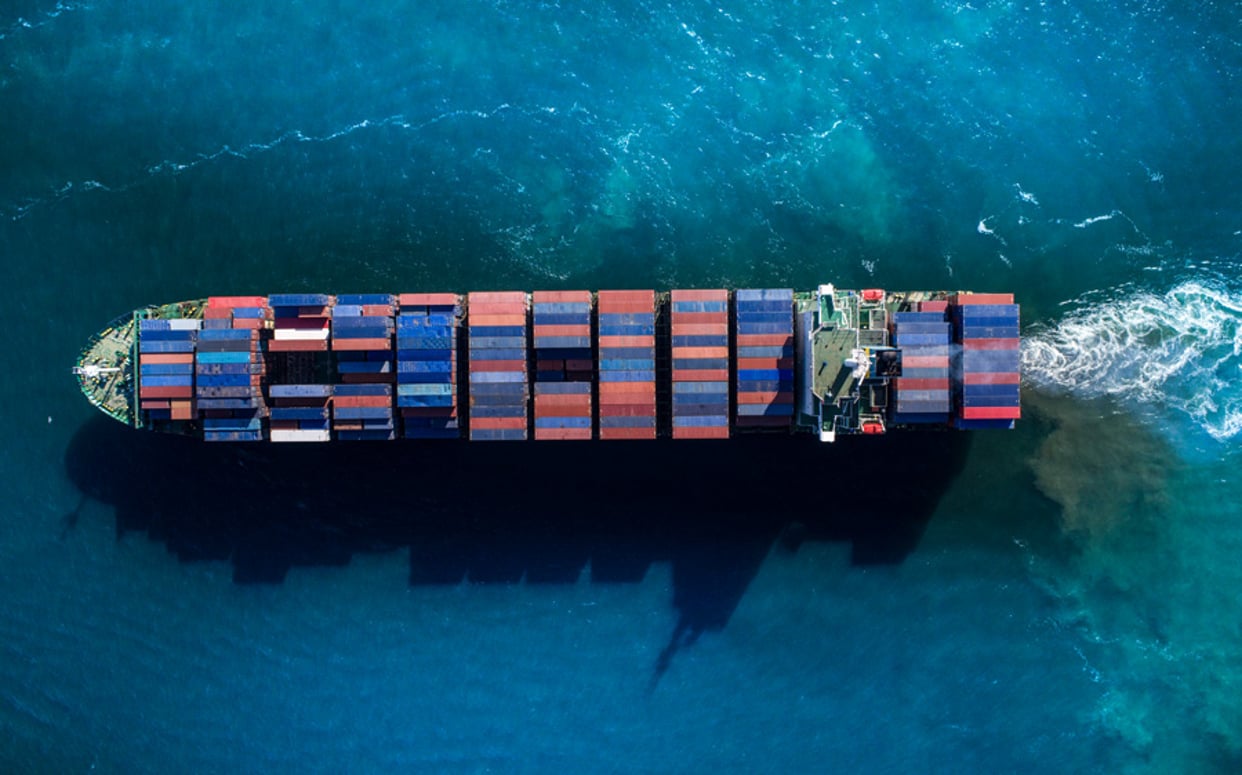 A large blue container ship carrying multi-colored freight across the ocean.
