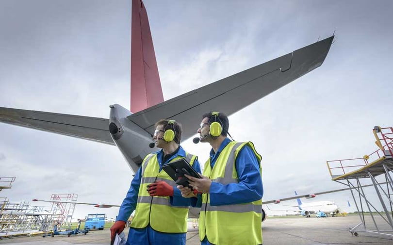 Image of two aircarft engineers and the tail of an aircraft